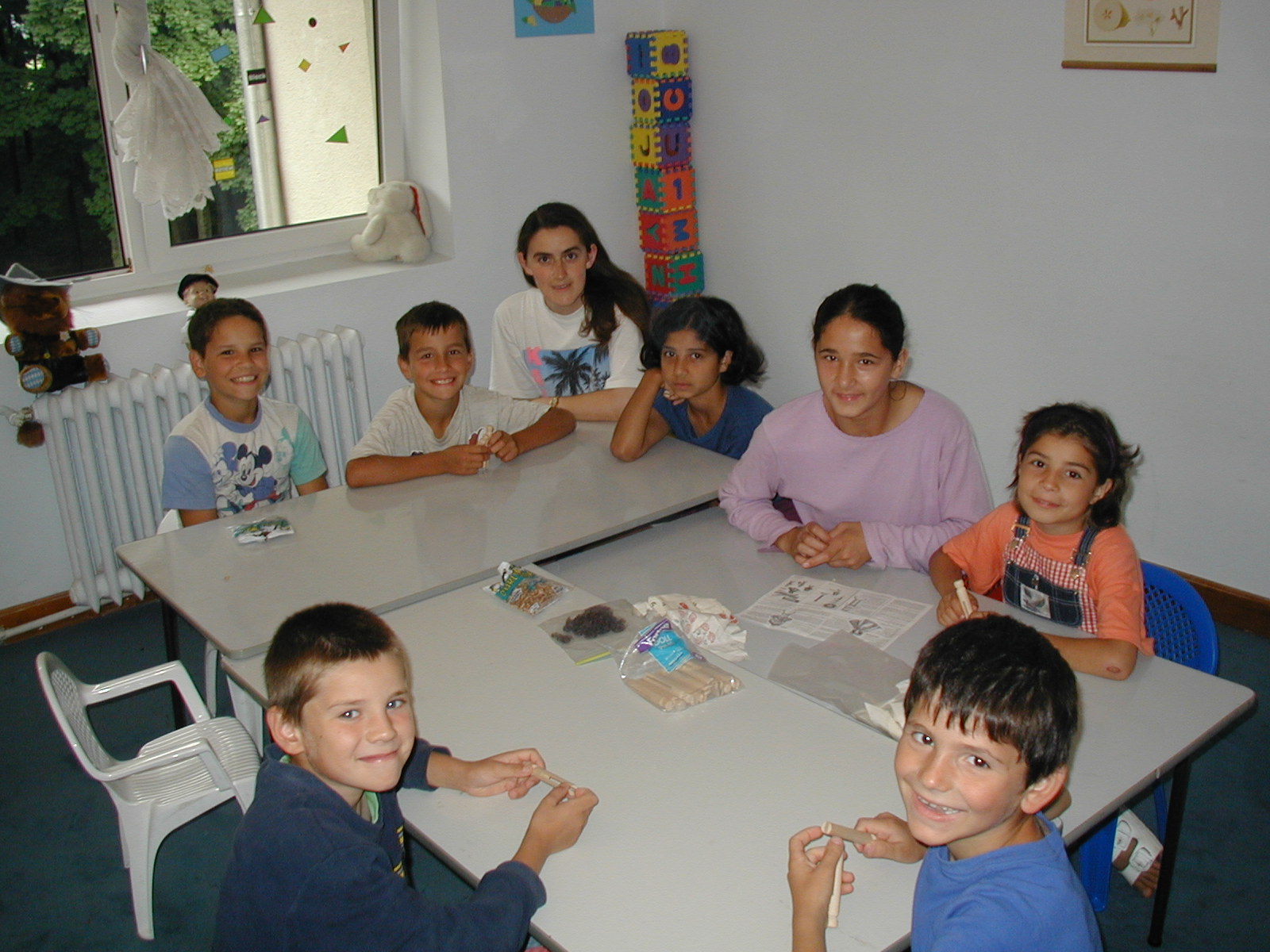 While it is raining outside the children make decorations with a caregiver.